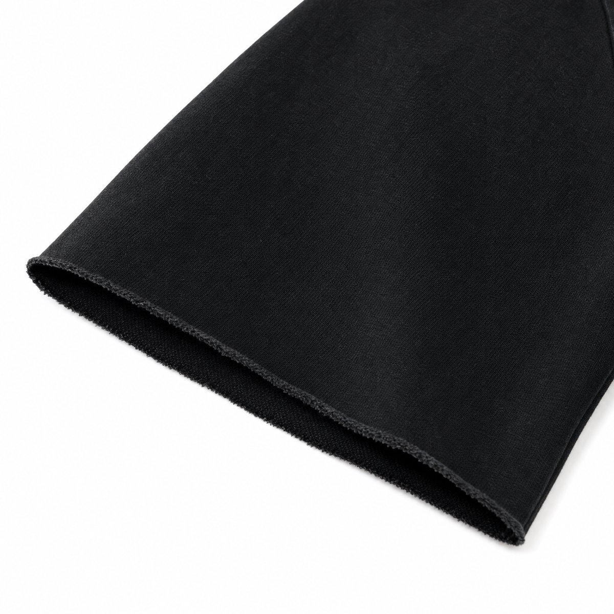 Close-up of The Statement Tee raw hem detail in Black, heavyweight cotton"