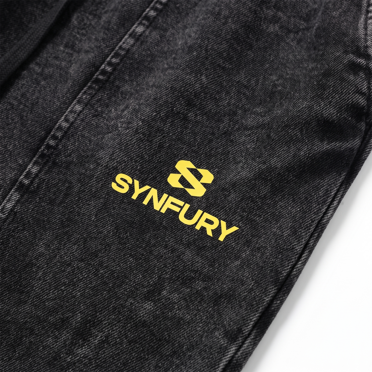 Close-up of yellow SYNFURY logo on The Unapologetic Hooded Set sweatpants in Cinder Black, heavyweight cotton"