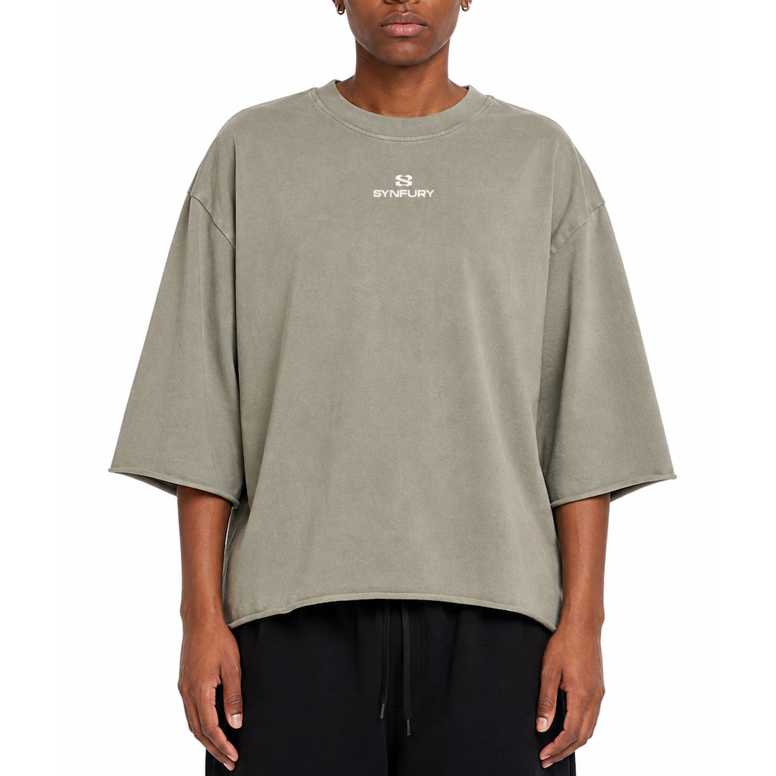 A model wearing an oversized, relaxed-fit crewneck t-shirt in a muted sage green color. The shirt features a small white 'SYNFURY' brand logo printed on the center chest.