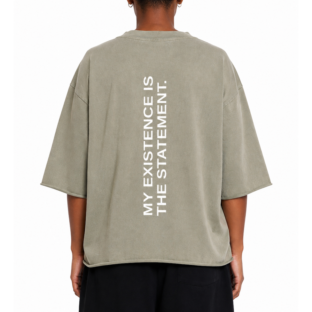 A person shown from the back wearing an oversized vintage clay t-shirt with vertical white text reading 'MY EXISTENCE IS THE STATEMENT.' on the back, paired with black pants against a plain white background.